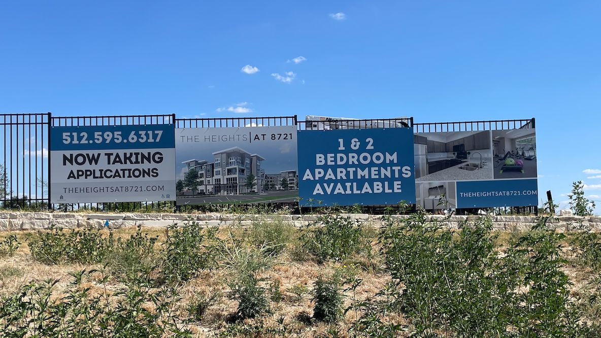 Apartment fence signs promoting leasing availability.