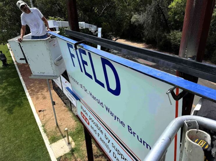 Large field sign being installed from a lift.