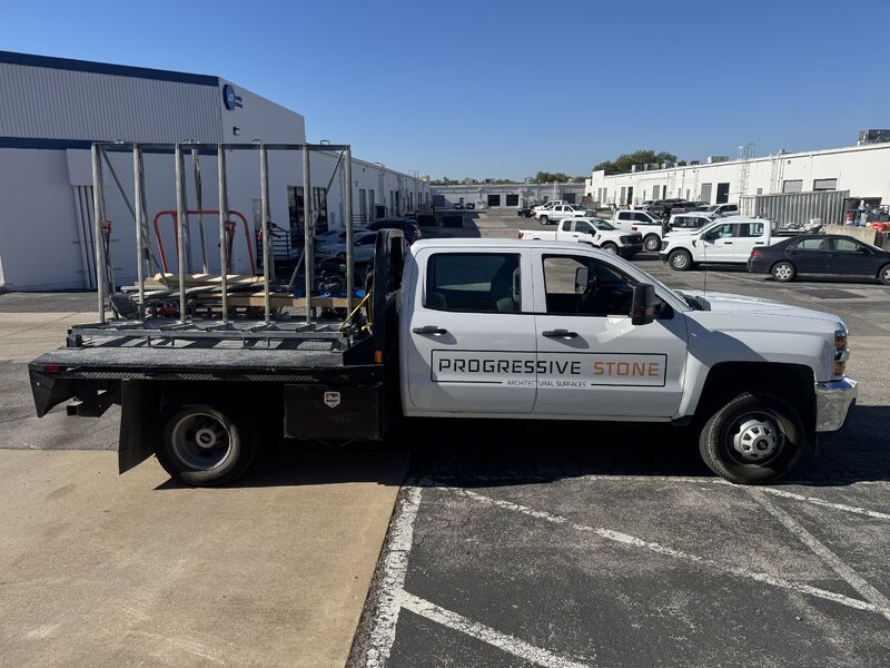 Progressive Stone branded work truck parked outside an industrial building.