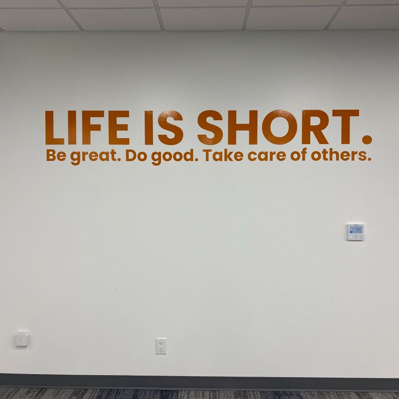 Large copper tone wall quote lettering installed inside an office.