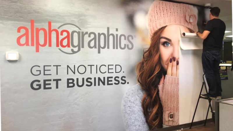 Large branded wall mural being installed in an office.